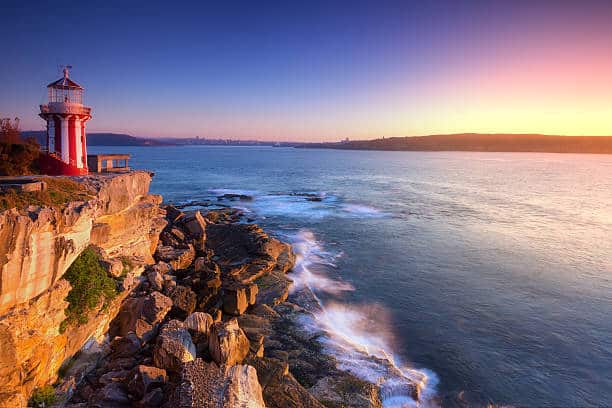 Sunrise seascape and red-white lighthouse.